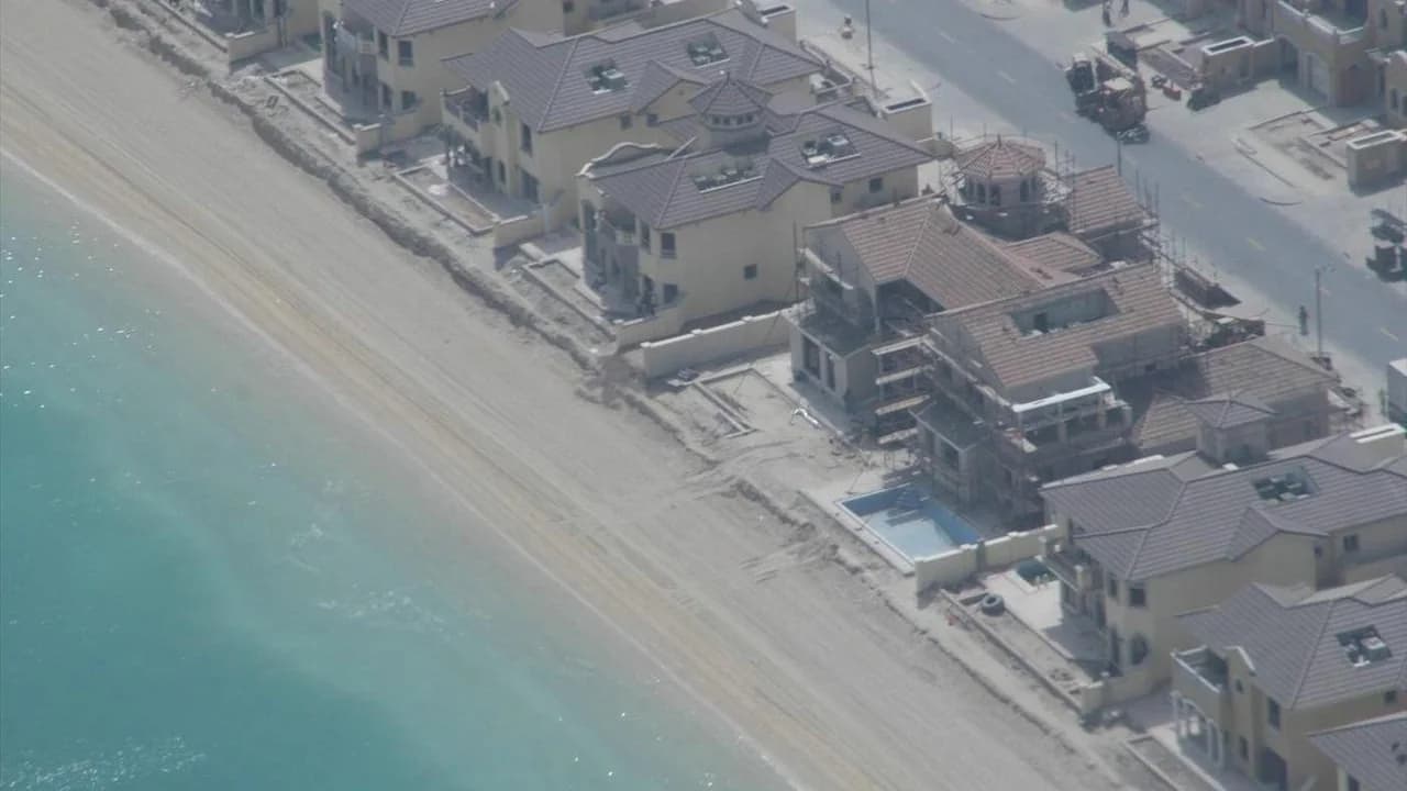 Aerial view of beachfront villas on a frond of Palm Jumeirah, several still under construction, beside the sea