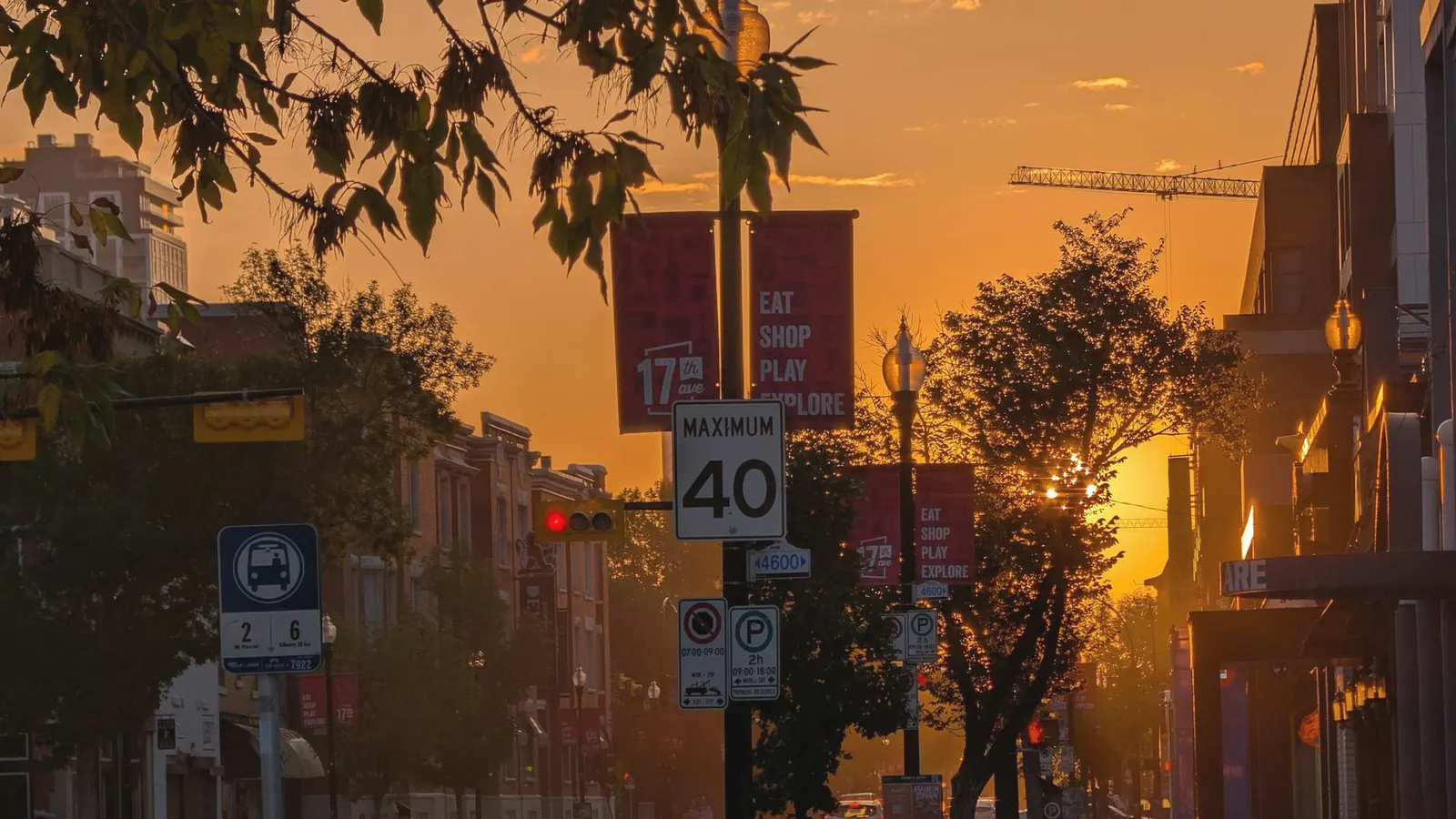 A quiet city street at golden hour, with long shadows across the pavement and warm light on the building fronts.