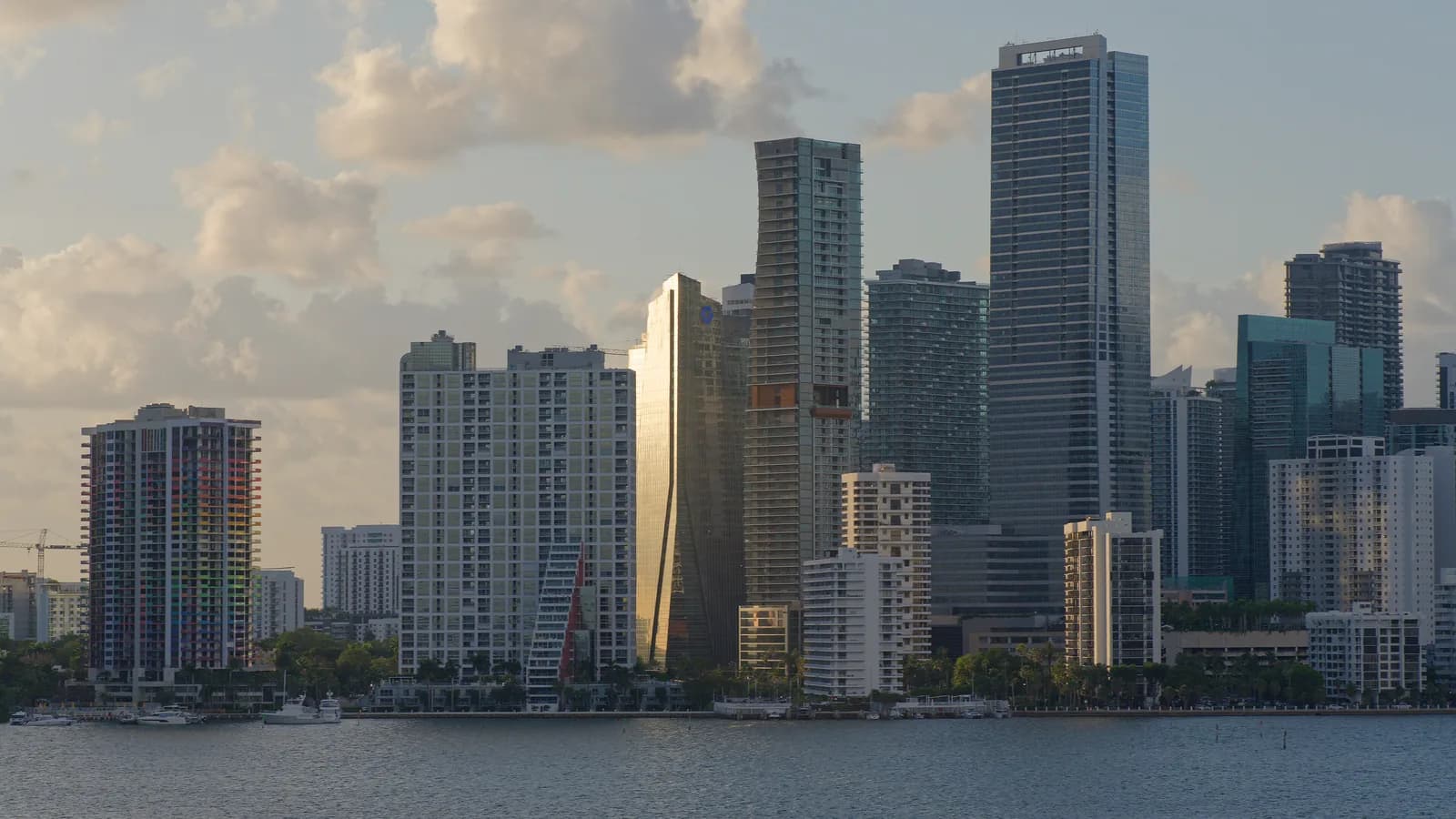 Brickell's condominium towers across Biscayne Bay in late-afternoon light, with low clouds above and calm water in front.