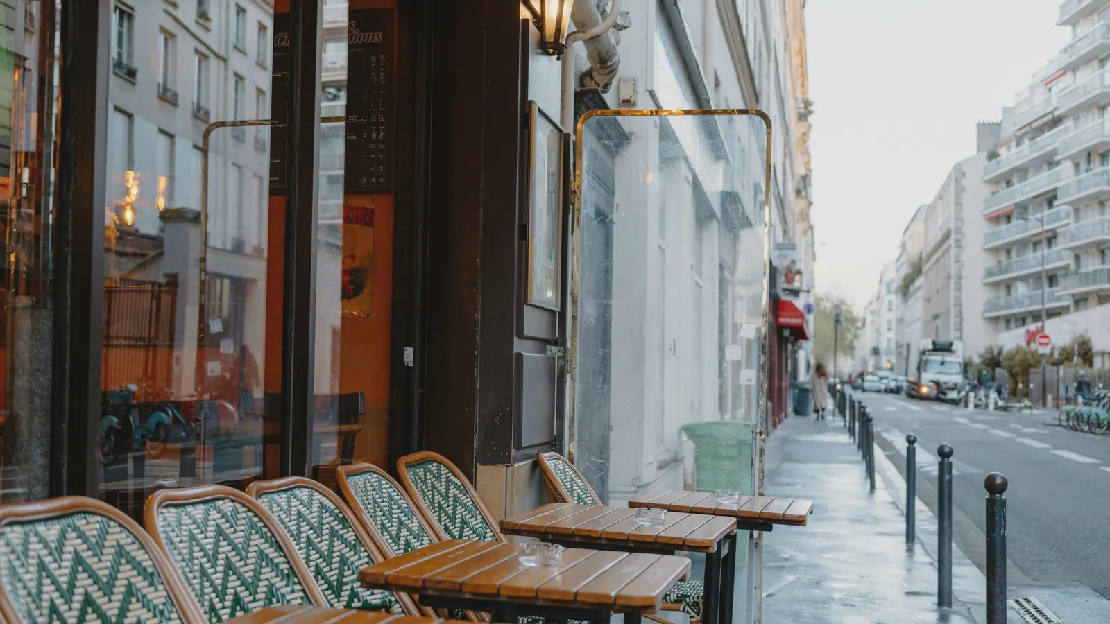 An empty café terrace of metal chairs on a residential city street.